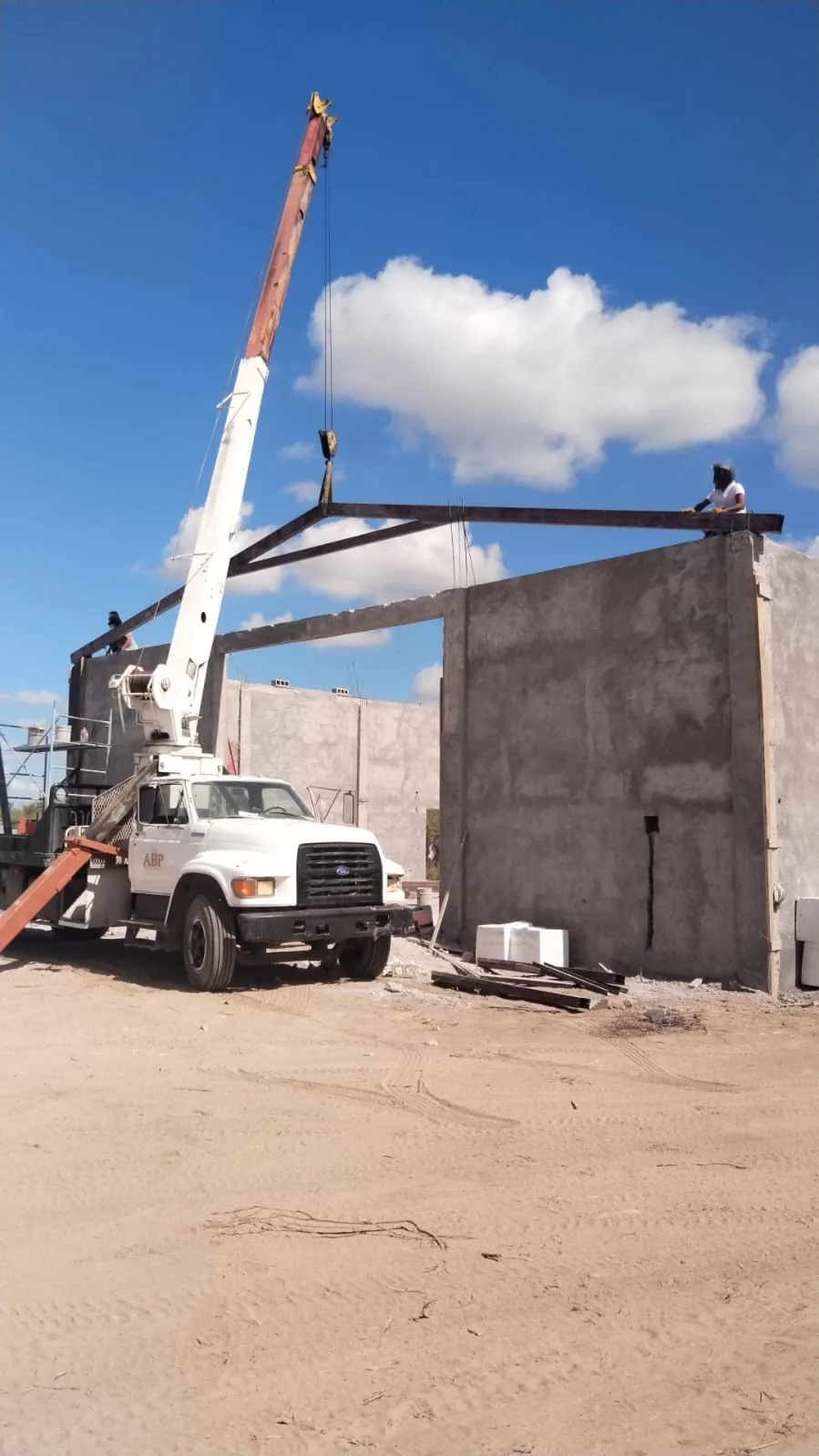Montaje de estructura metálica sobre muros de block en obra negra, con grúa titán